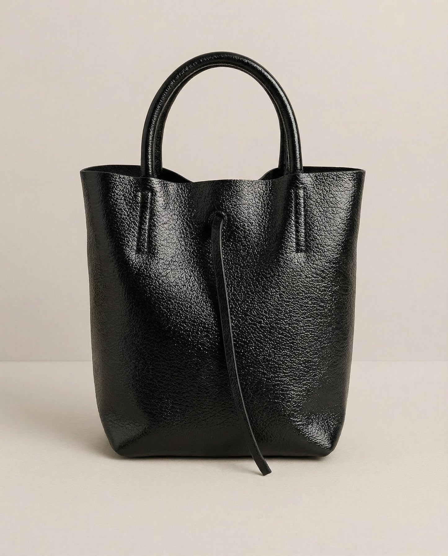 Mini tote in metallic black leather with structured silhouette and top handles, sleek and compact design.