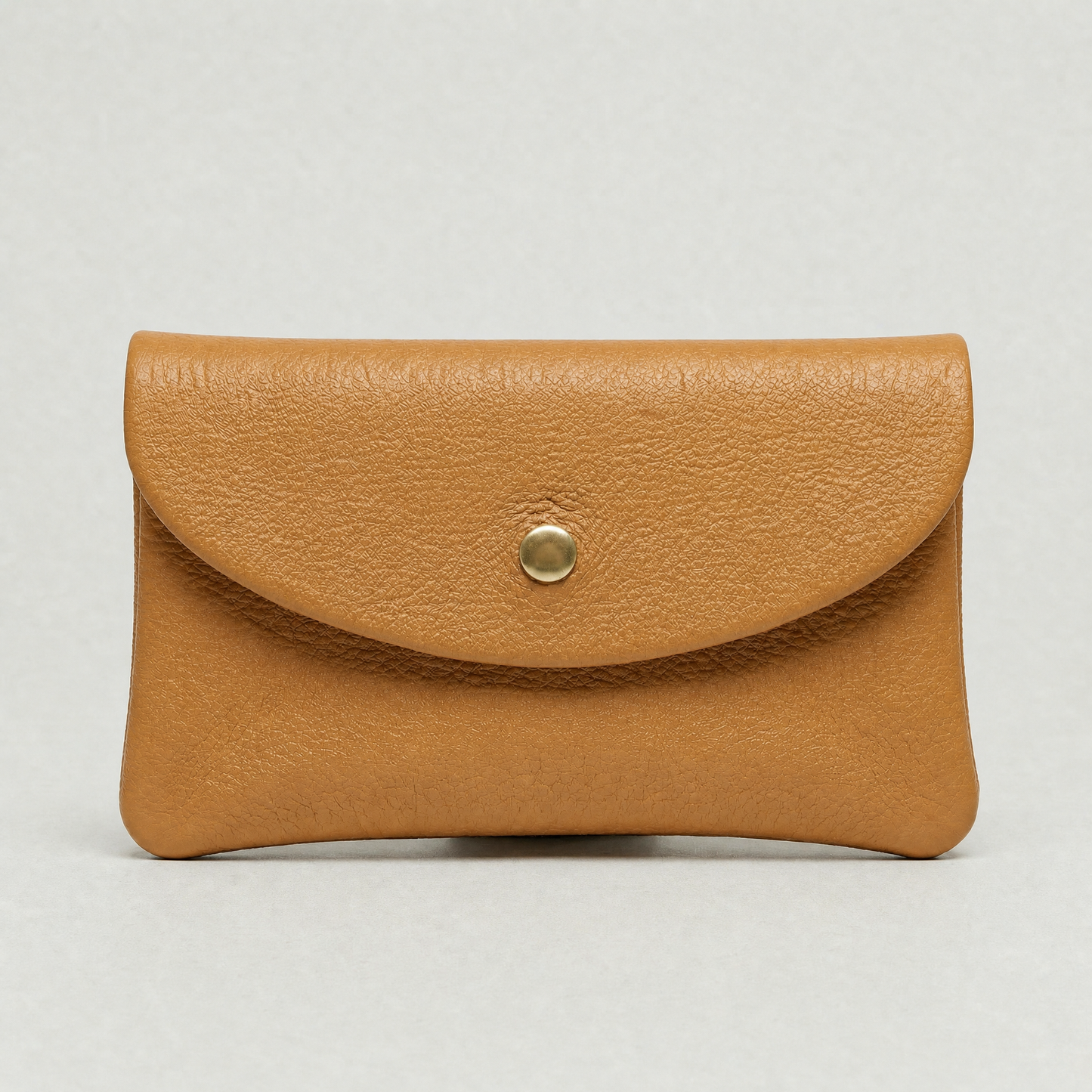 Camel leather wallet with a gold button on a light gray background
