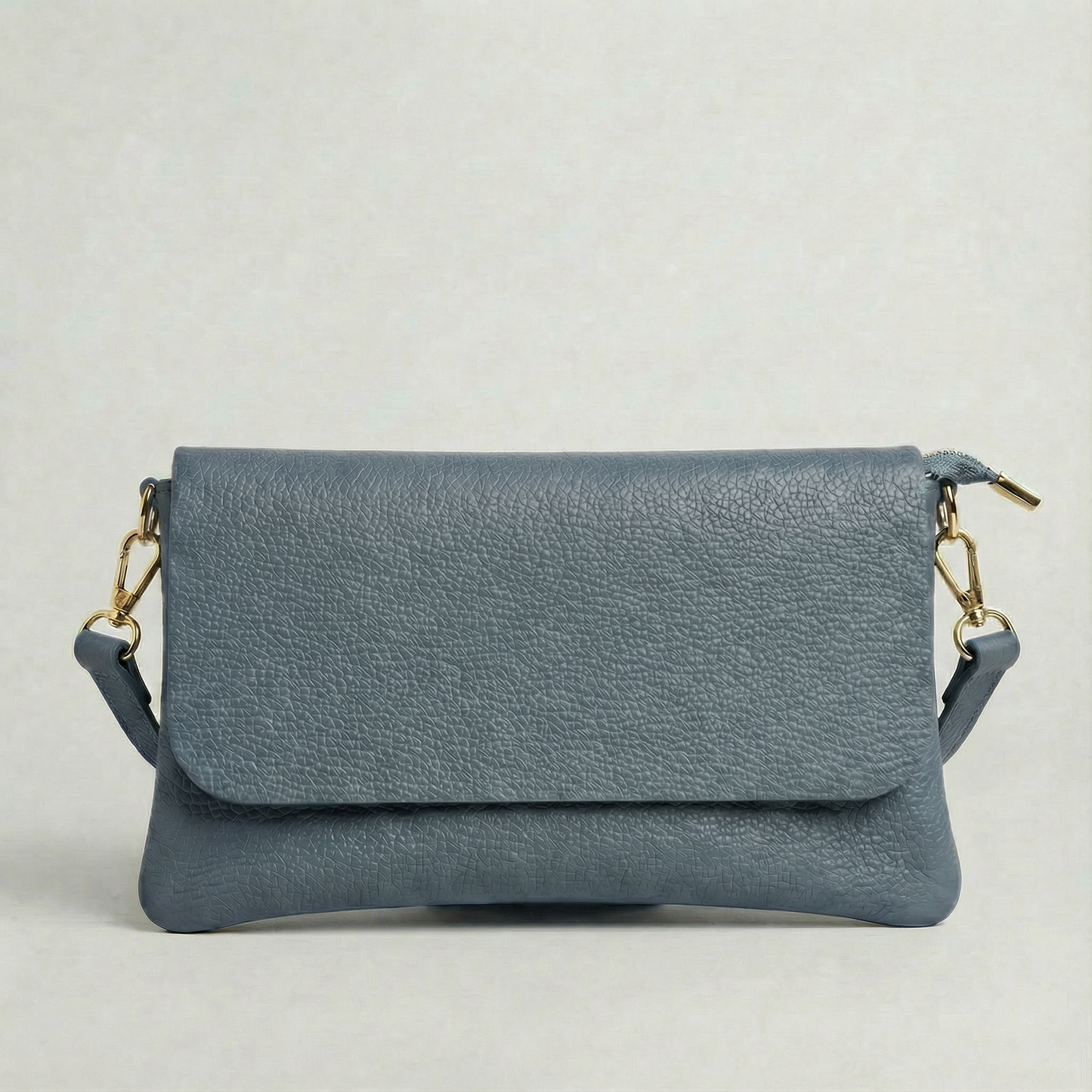 Denim pebble leather crossbody bag with a matching color adjustable strap, displayed on a light gray background.