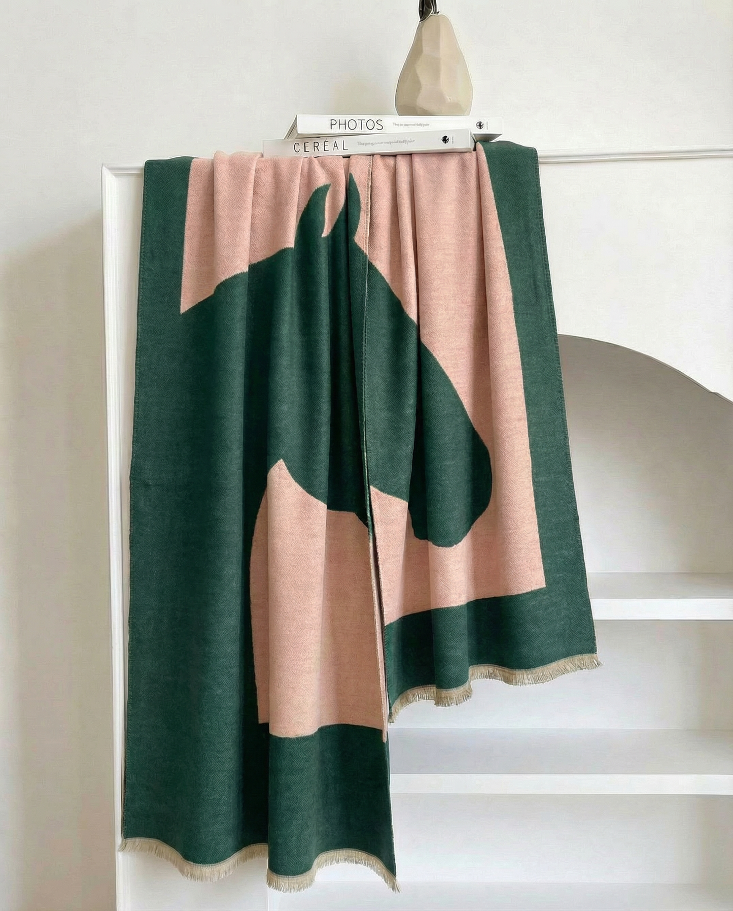 Green and beige wrap with horse-head motiv draped over a white surface