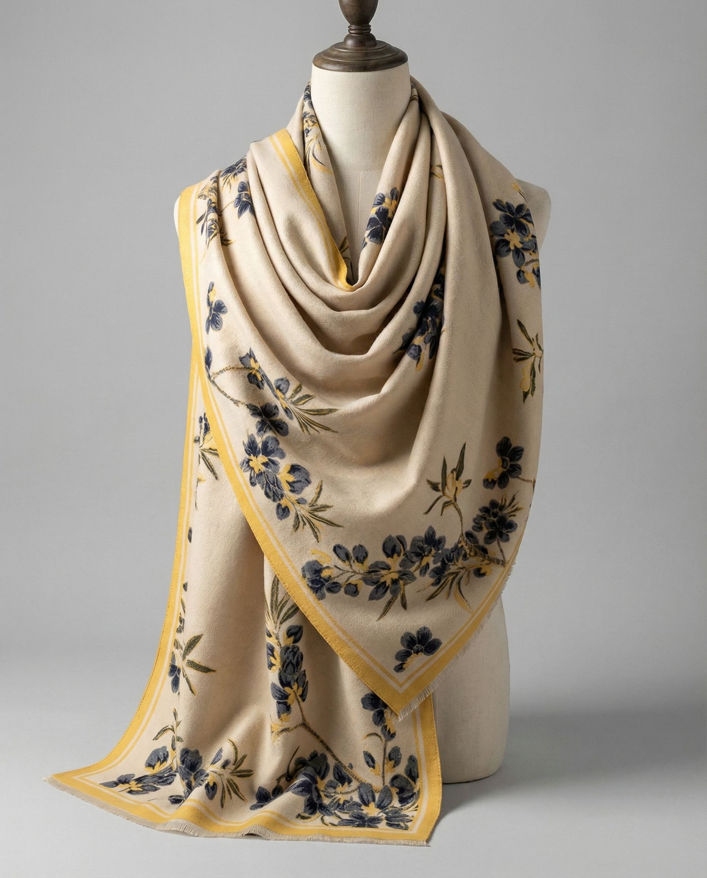 Beige wrap with floral pattern on a mannequin against a gray background