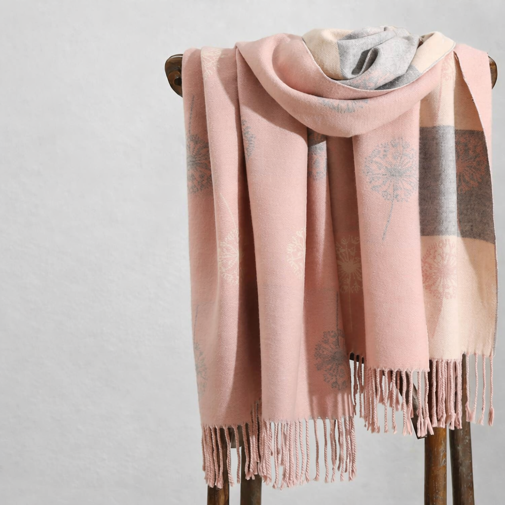 Pink wrap with fringe on a wooden stand against a light gray background