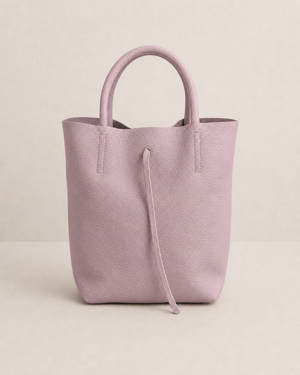 Lilac pebble leather mini tote with structured silhouette, detachable crossbody strap, compact interior, and genuine Italian craftsmanship.