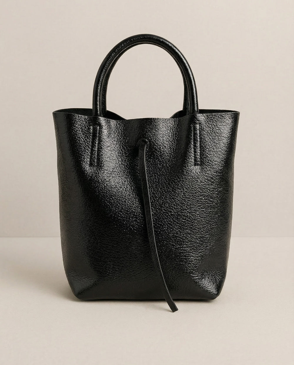 Mini tote in metallic black leather with structured silhouette and top handles, sleek and compact design.