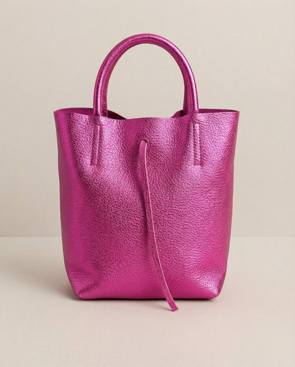 Mini tote in metallic magenta leather with structured silhouette and top handles, sleek and compact design.