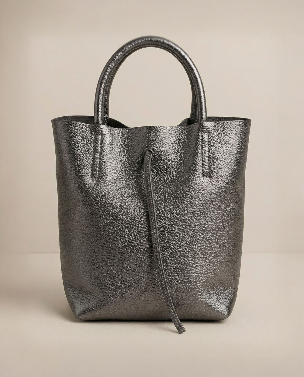 Mini tote in metallic pewter leather with structured silhouette and top handles, sleek and compact design.