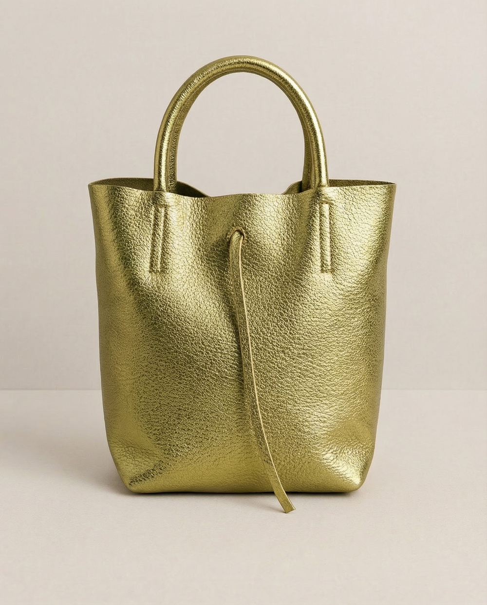 Mini tote in metallic pistachio leather with structured silhouette and top handles, sleek and compact design.