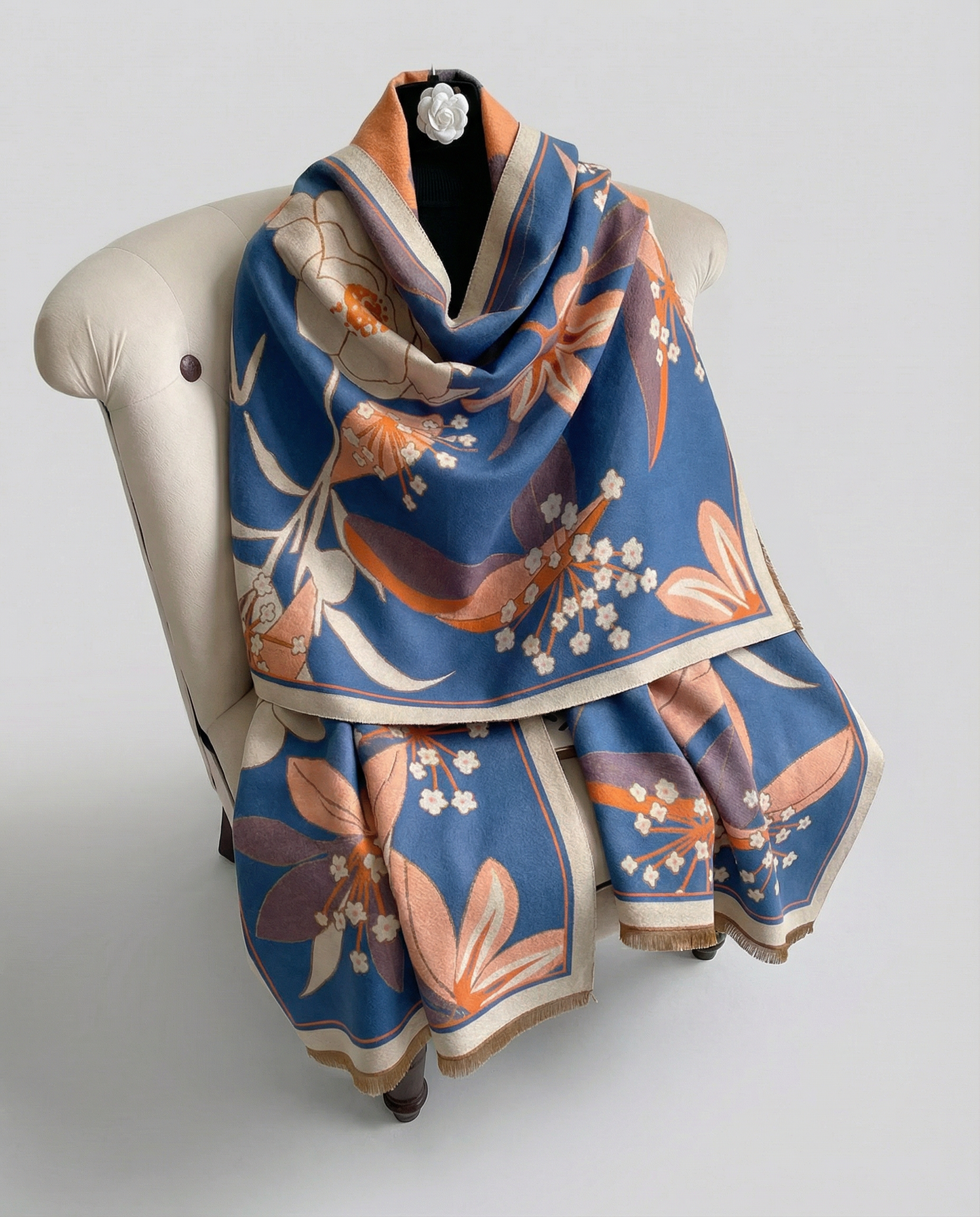 Blue wrap with orange floral patterned draped on a chair on a light gray background