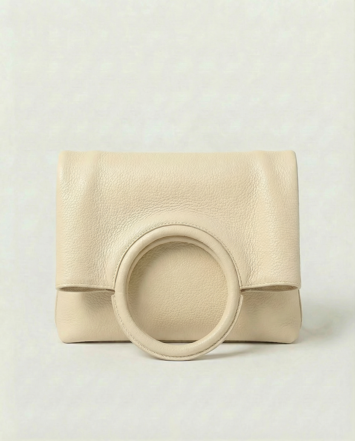 Ring Bag in pebble leather ivory with circular ring handle and structured silhouette.
