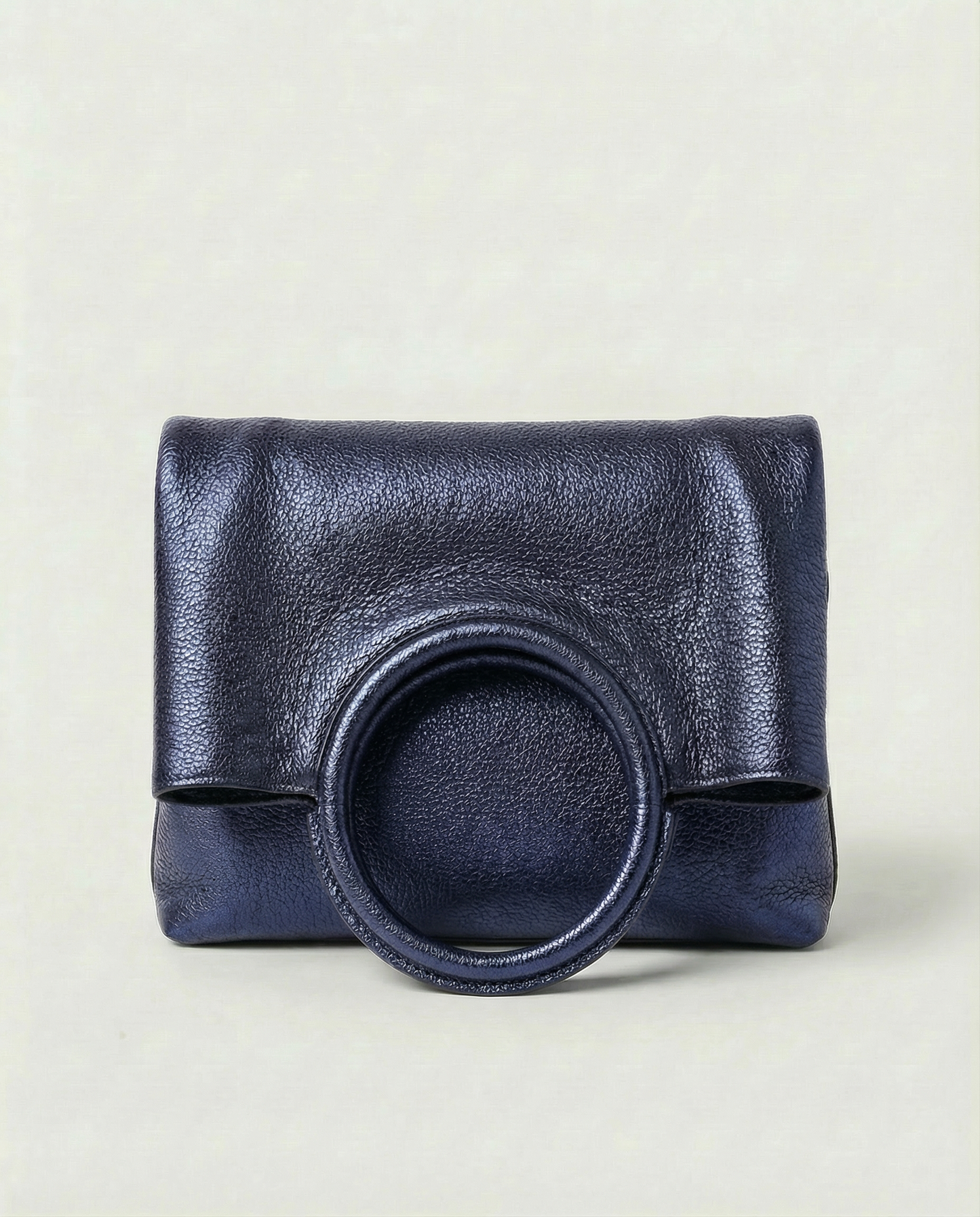Metallic indigo leather ring bag with circular top handle and structured silhouette, sleek and modern design.