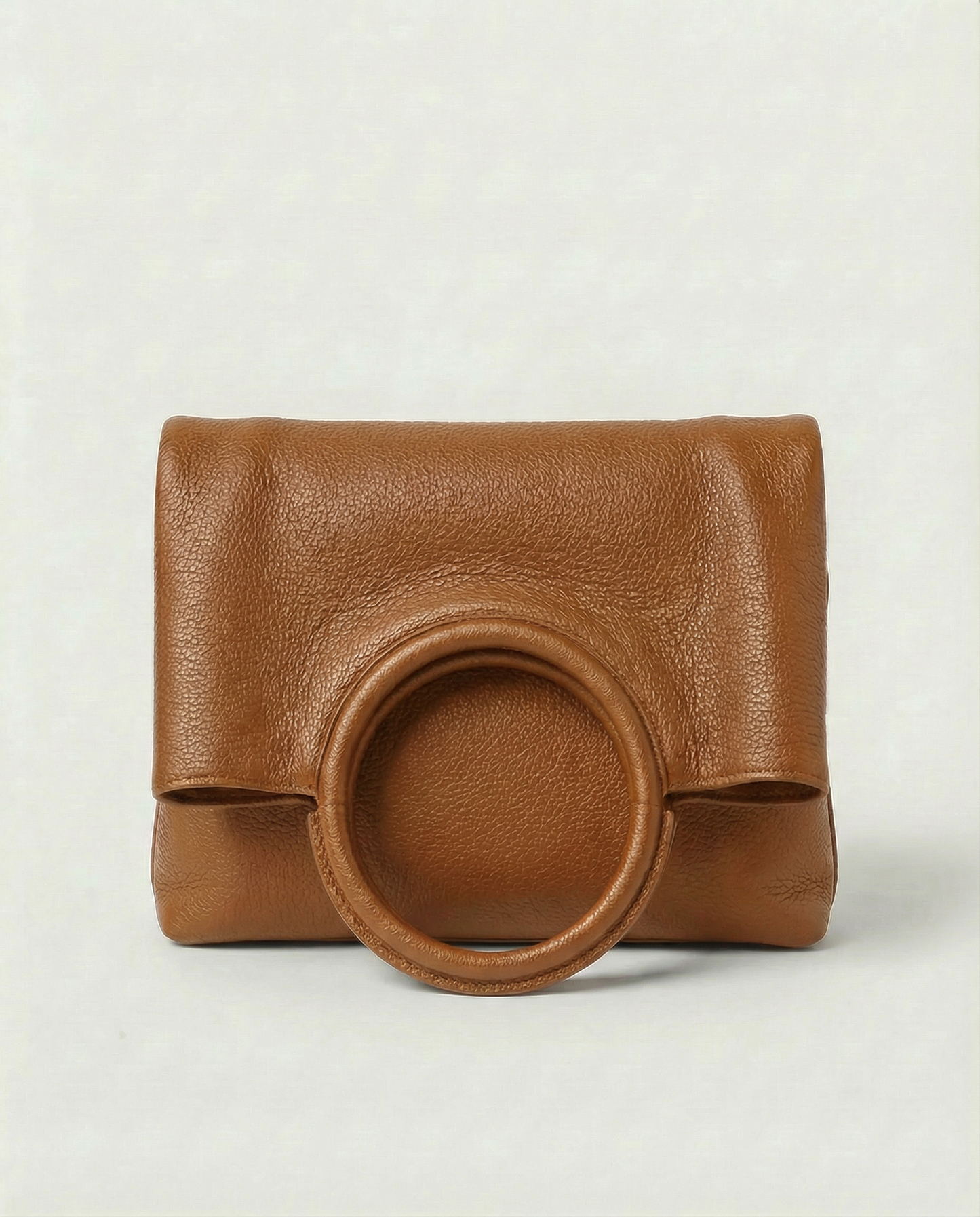Ring Bag in pebble leather caramel with circular ring handle and structured silhouette.