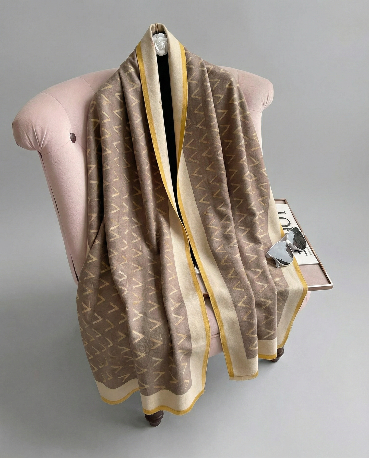 Brown patterned wrap draped over a pink cushion on a gray background