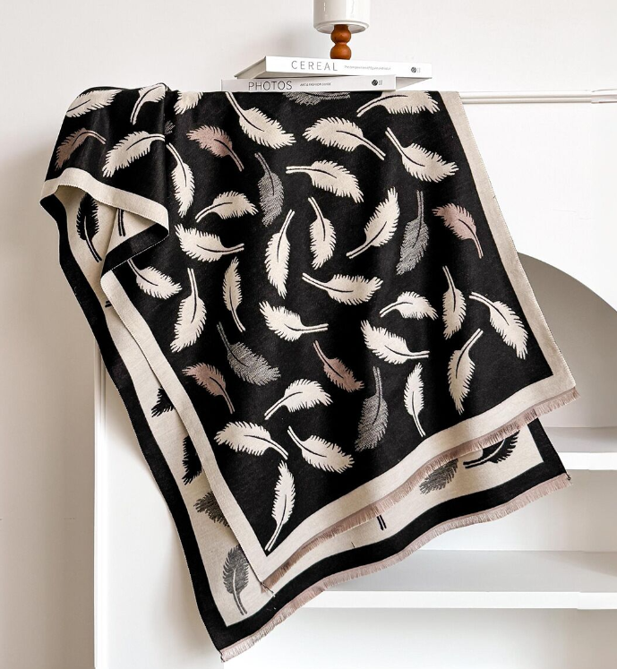 Black wrap with feather pattern draped over a white surface