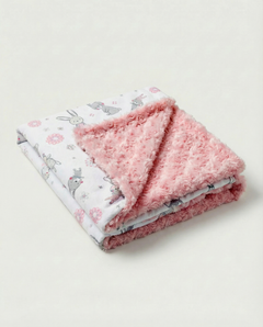 Folded pink blanket with floral and animal pattern on a light background, view 1
