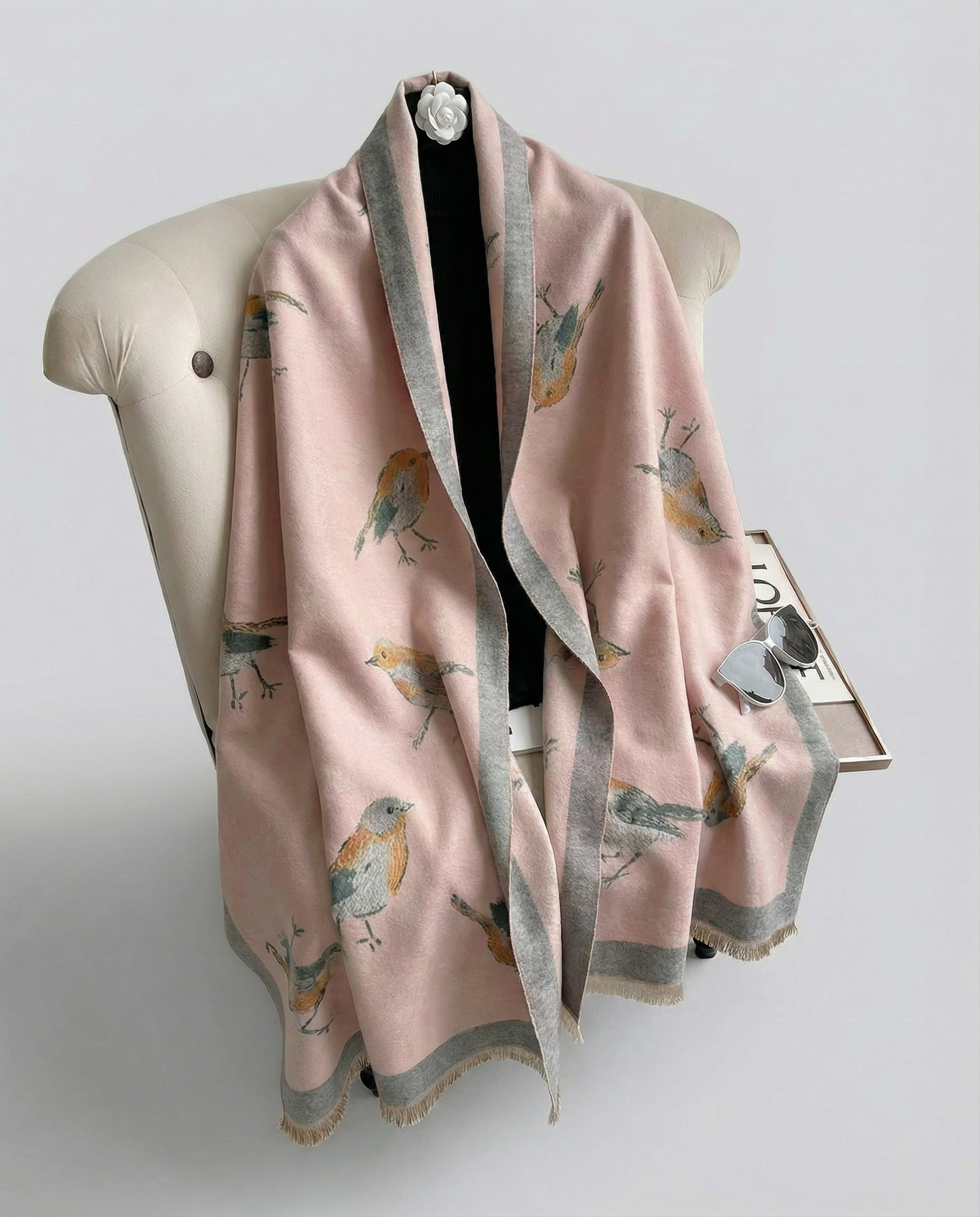 Pink wrap with bird pattern draped over a chair on a light gray background