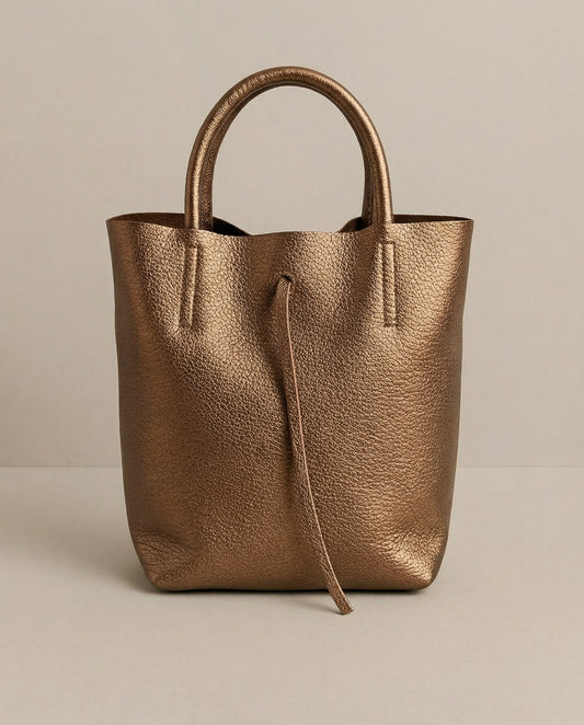 Mini tote in metallic bronze leather with structured silhouette and top handles, sleek and compact design. 