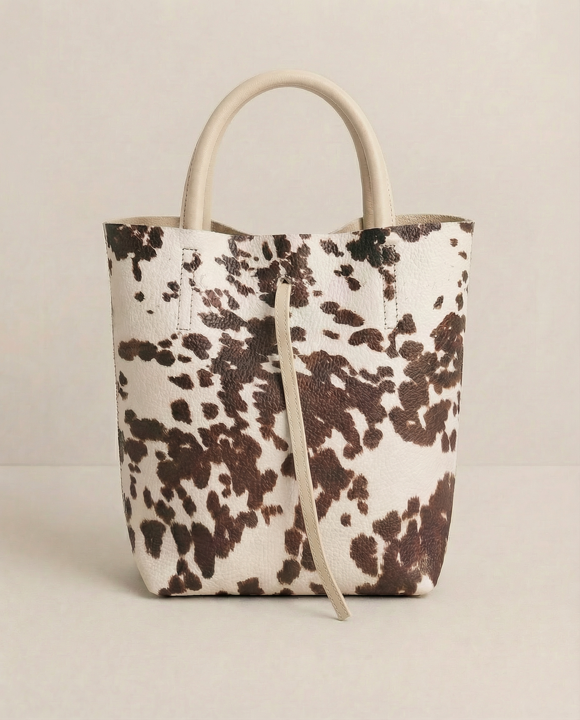 Mini tote in pebble leather cow with structured silhouette and top handles, compact and bold design.
