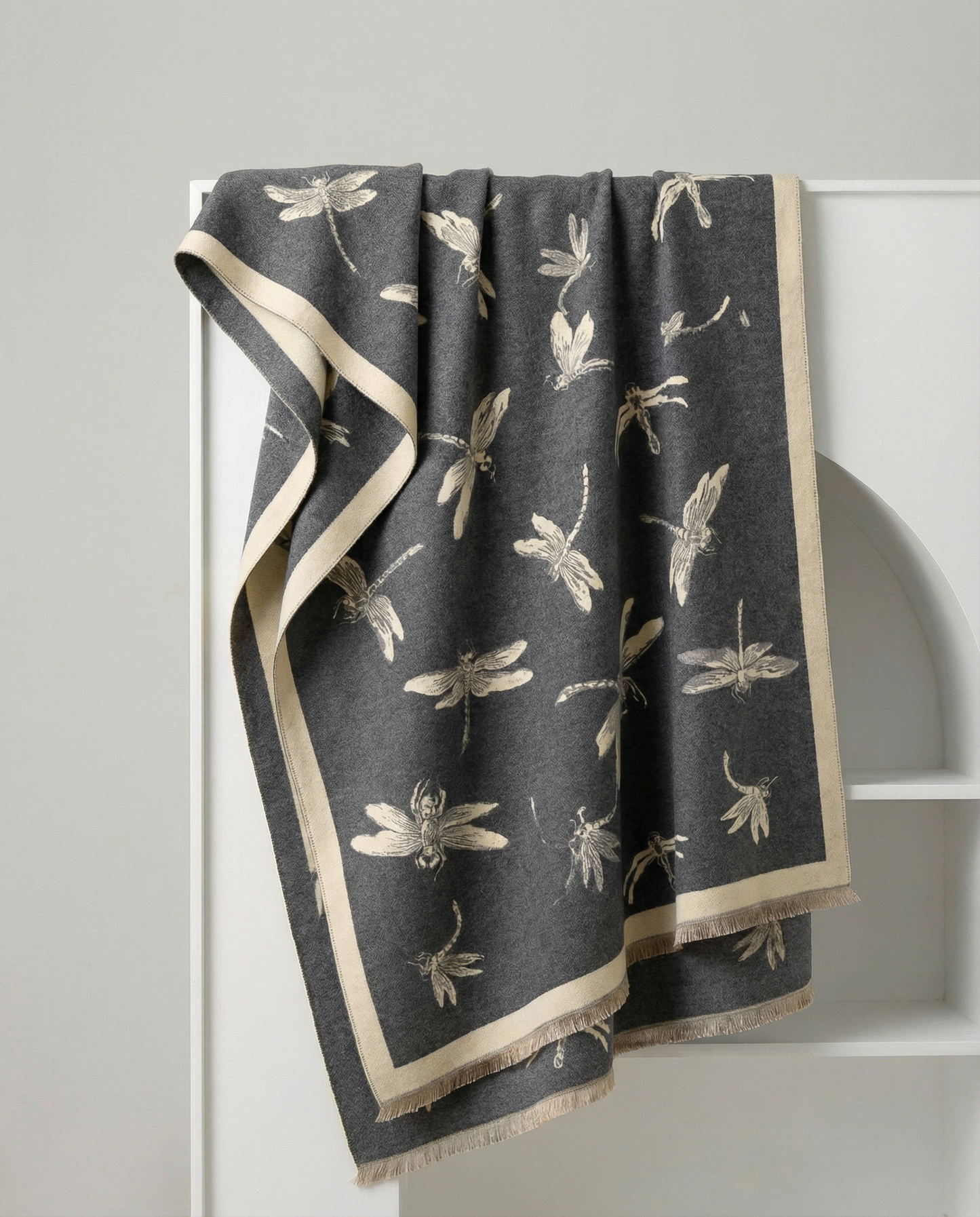Dark gray wrap with beige dragonfly pattern draped over a white rack.