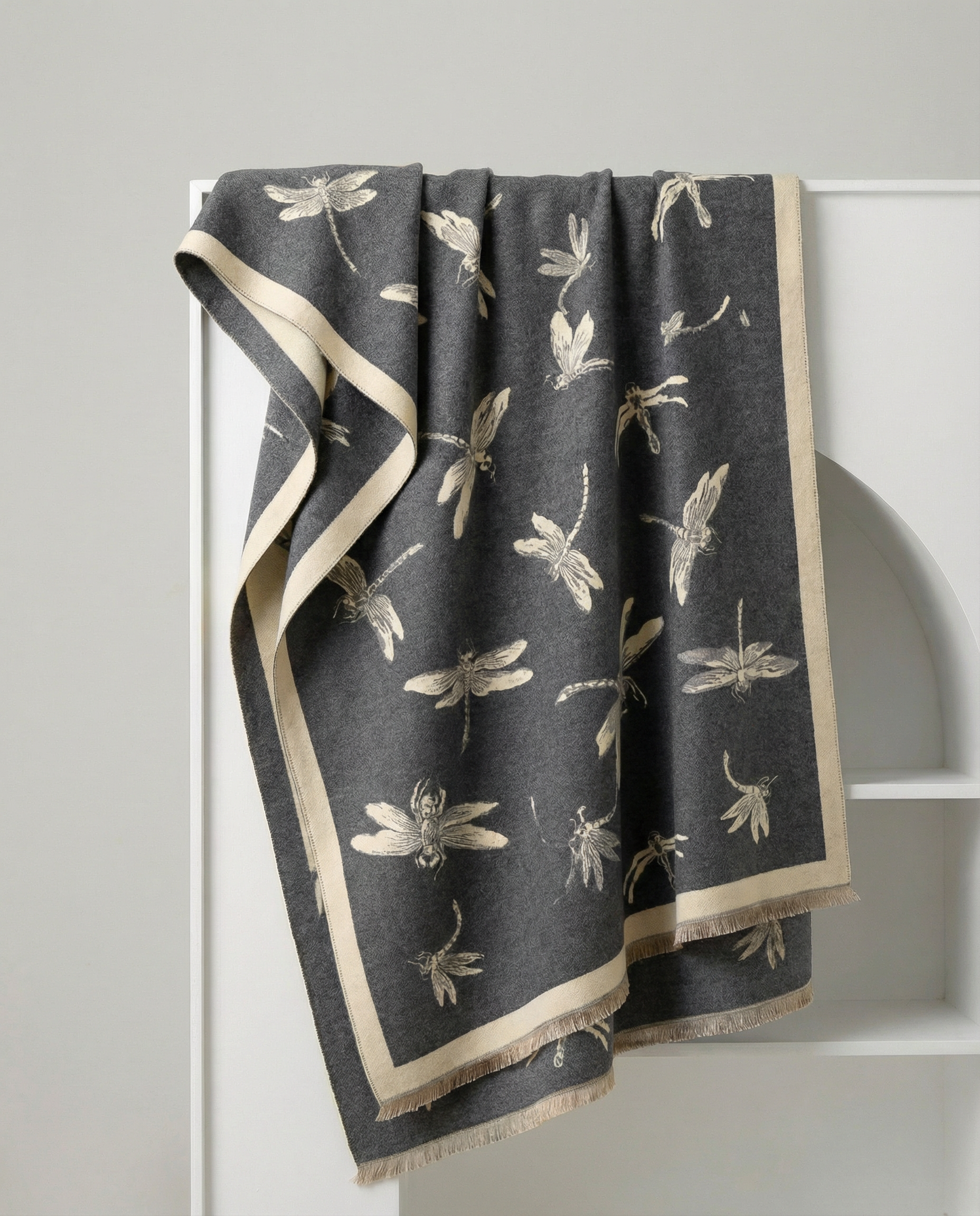 Dark gray wrap with beige dragonfly pattern draped over a white rack.