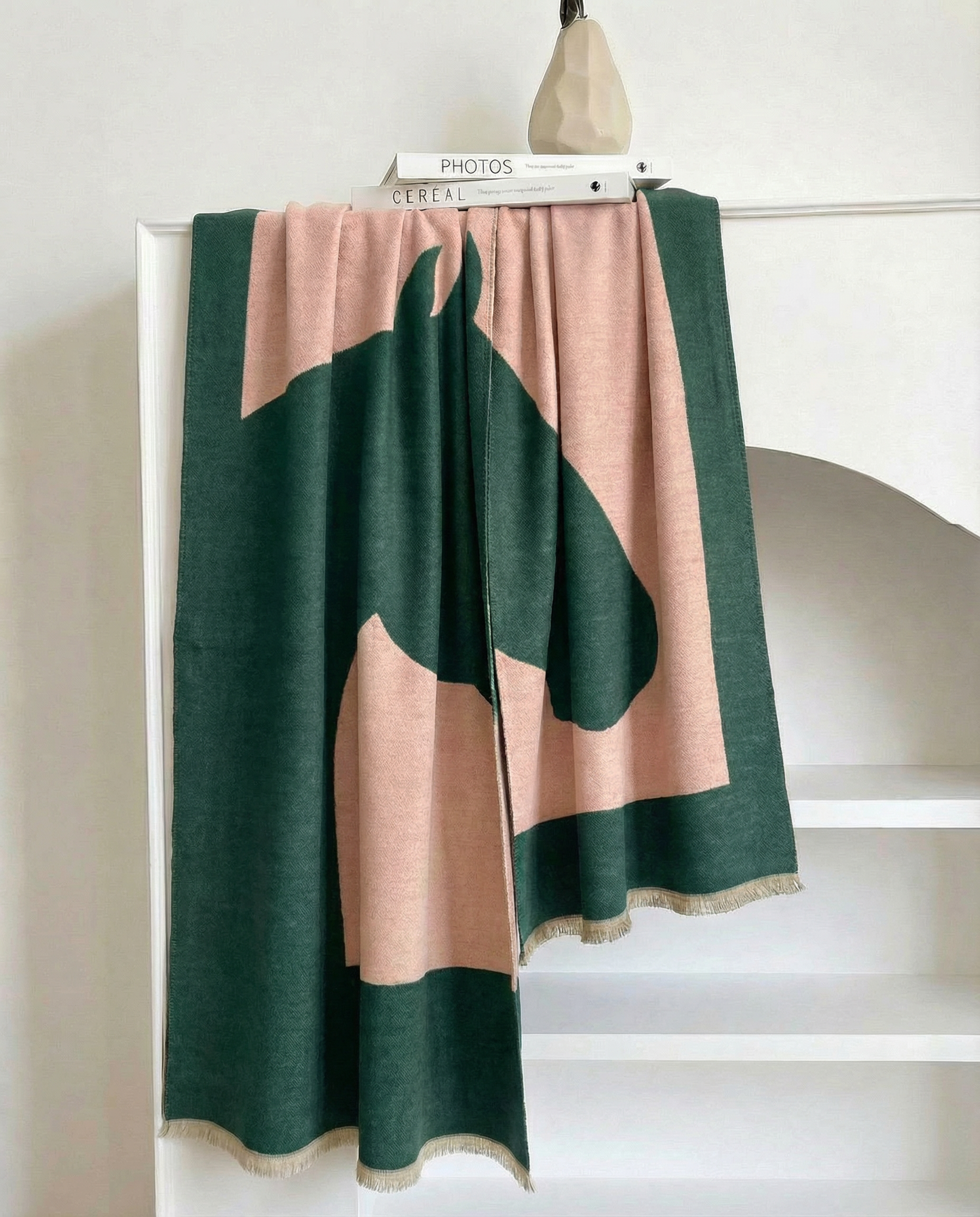 Green and beige wrap with horse-head motiv draped over a white surface