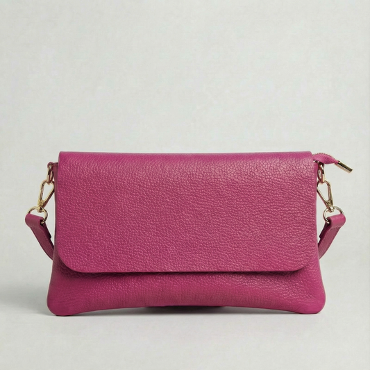 Magenta pebble leather crossbody bag with a matching color adjustable strap, displayed on a light gray background.