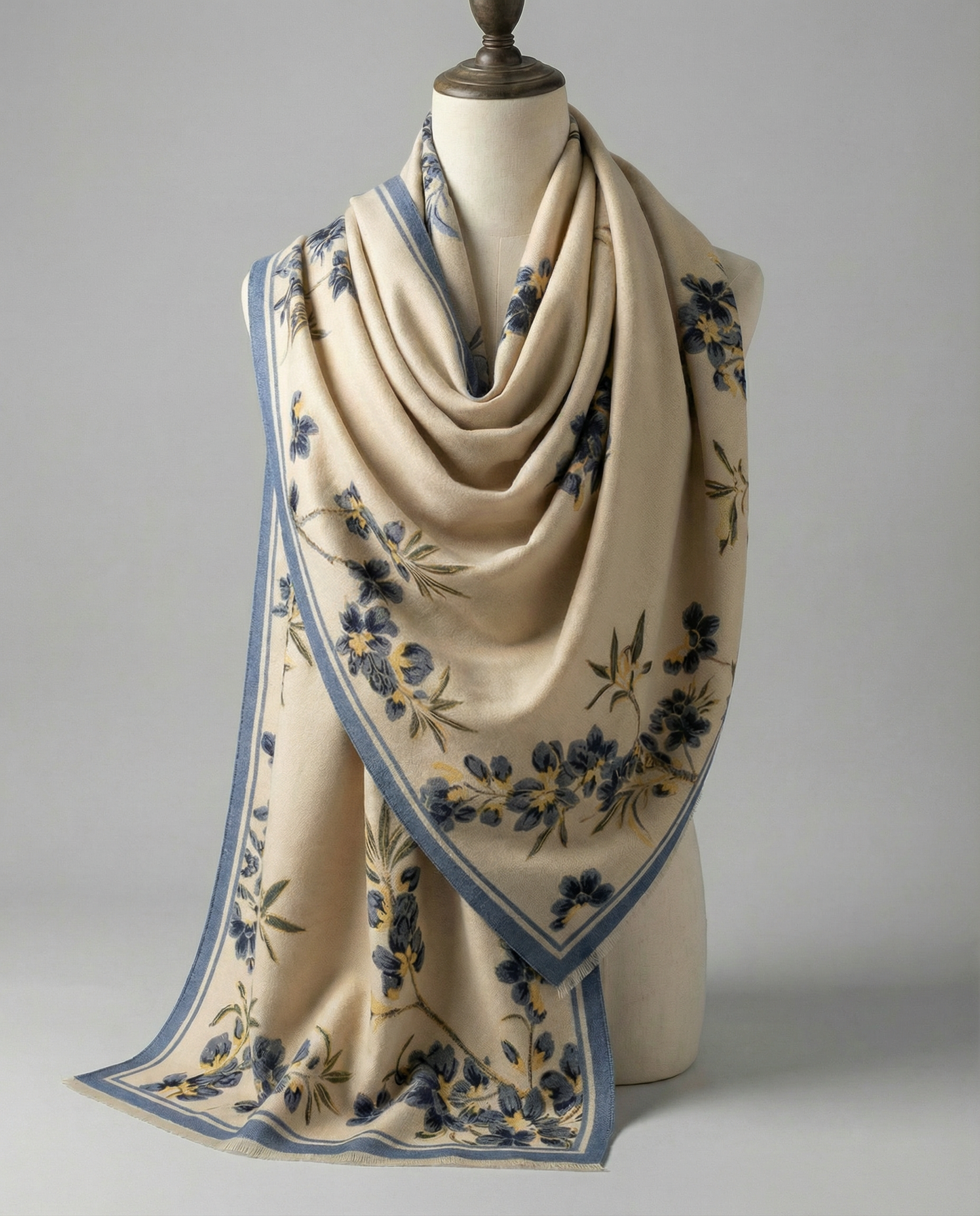 Beige wrap with floral patterns on a mannequin against a gray background