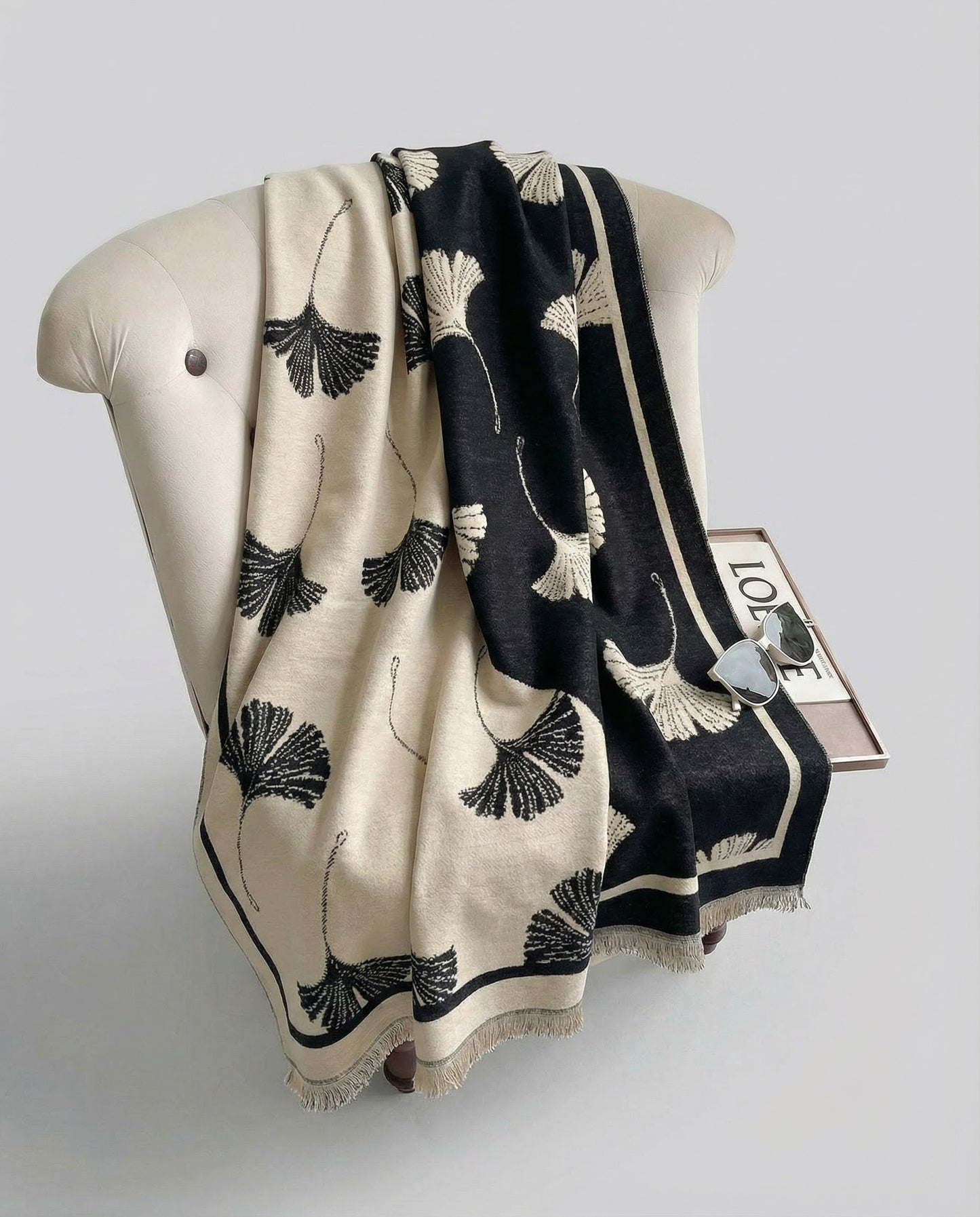 Black and beige patterned wrap draped on a chair on a light gray background.