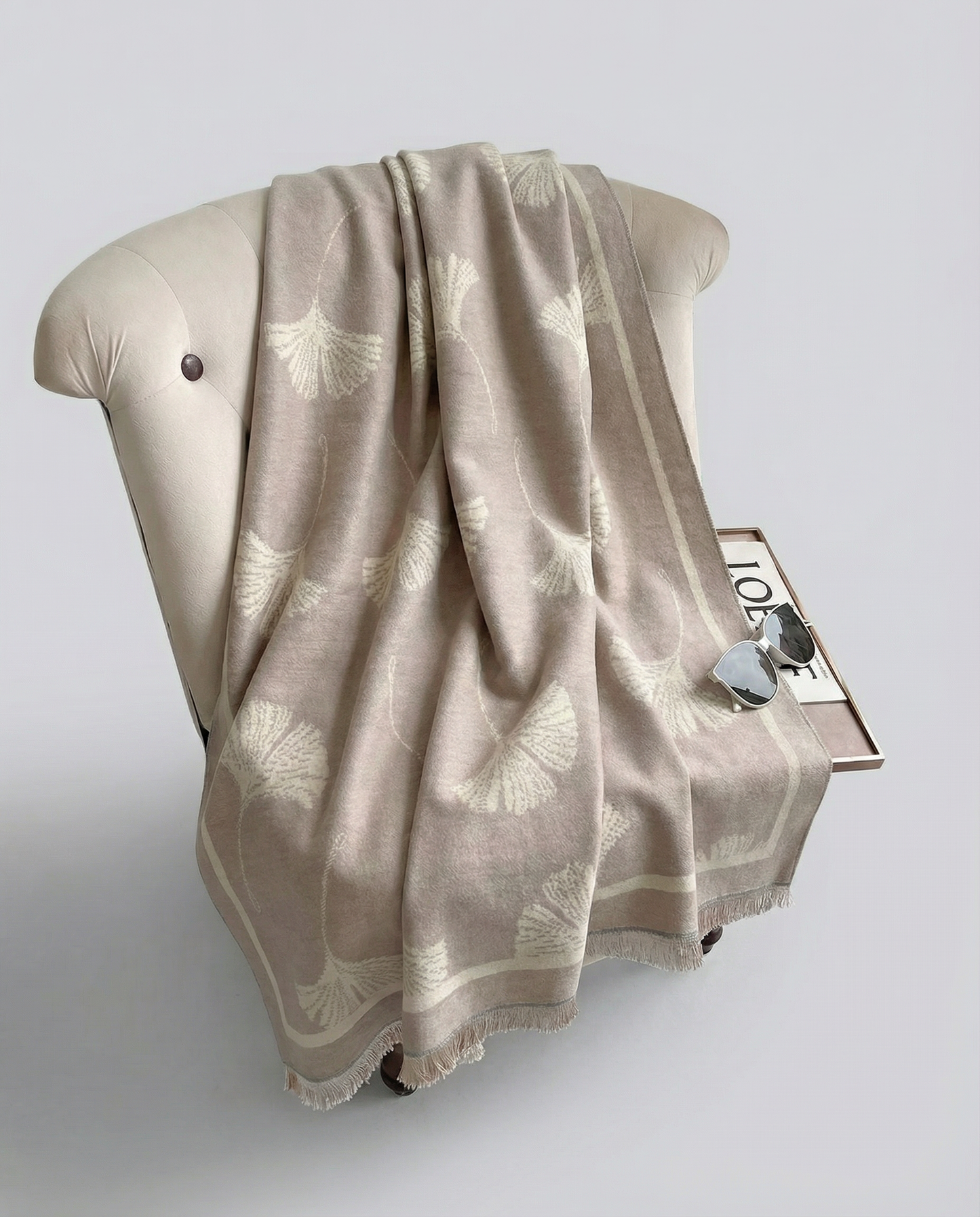 Beige patterned blanket draped over a beige armchair on a light gray background
