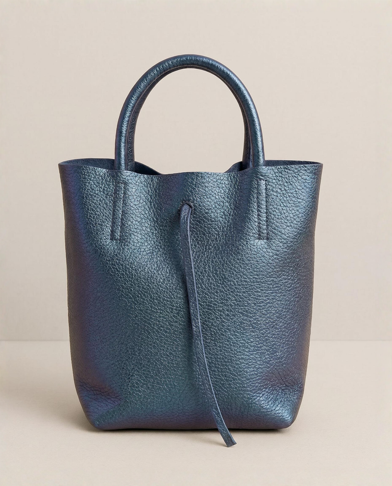 Mini tote in metallic denim leather with structured silhouette and top handles, sleek and compact design. 