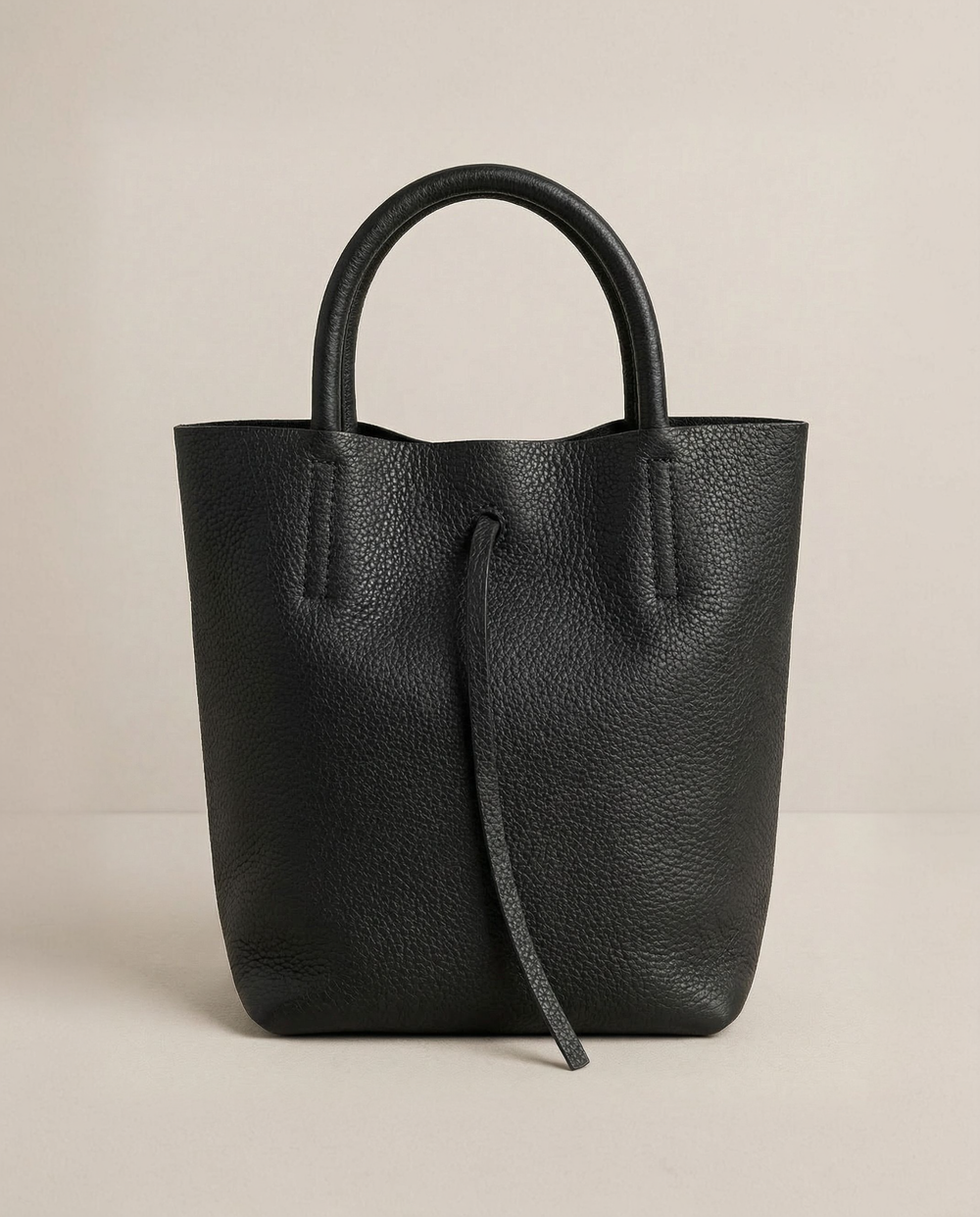 Black pebble leather mini tote with structured silhouette, detachable crossbody strap, compact interior, and genuine Italian craftsmanship.