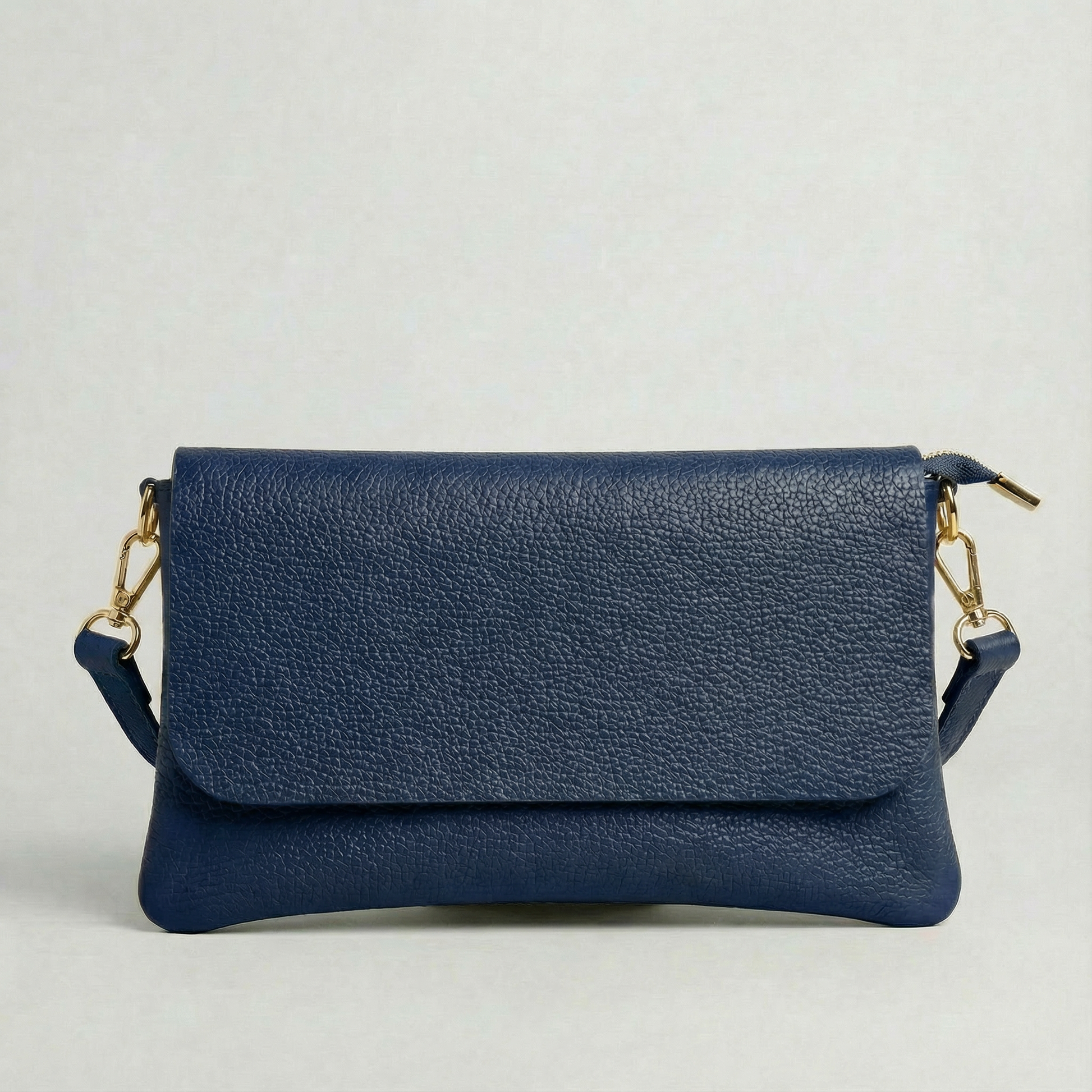 Navy pebble leather crossbody bag with a matching color adjustable strap, displayed on a light gray background.