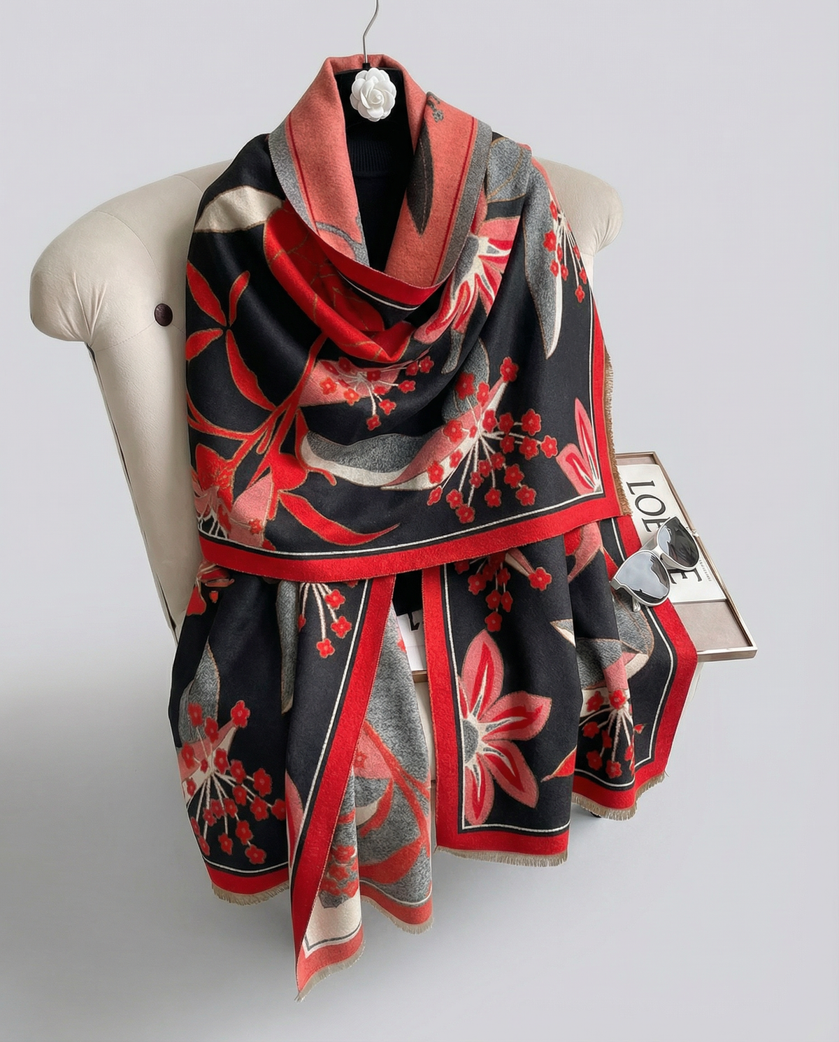 Scarf with red and black floral pattern on a chair against a white background