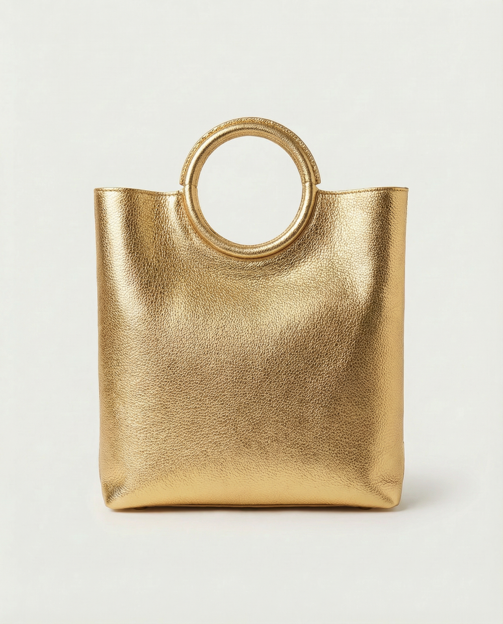 Gold metallic ring bag with circular handles on a light gray background