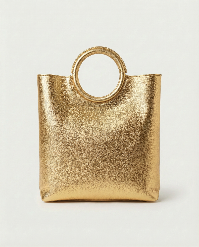 Gold metallic ring bag with circular handles on a light gray background