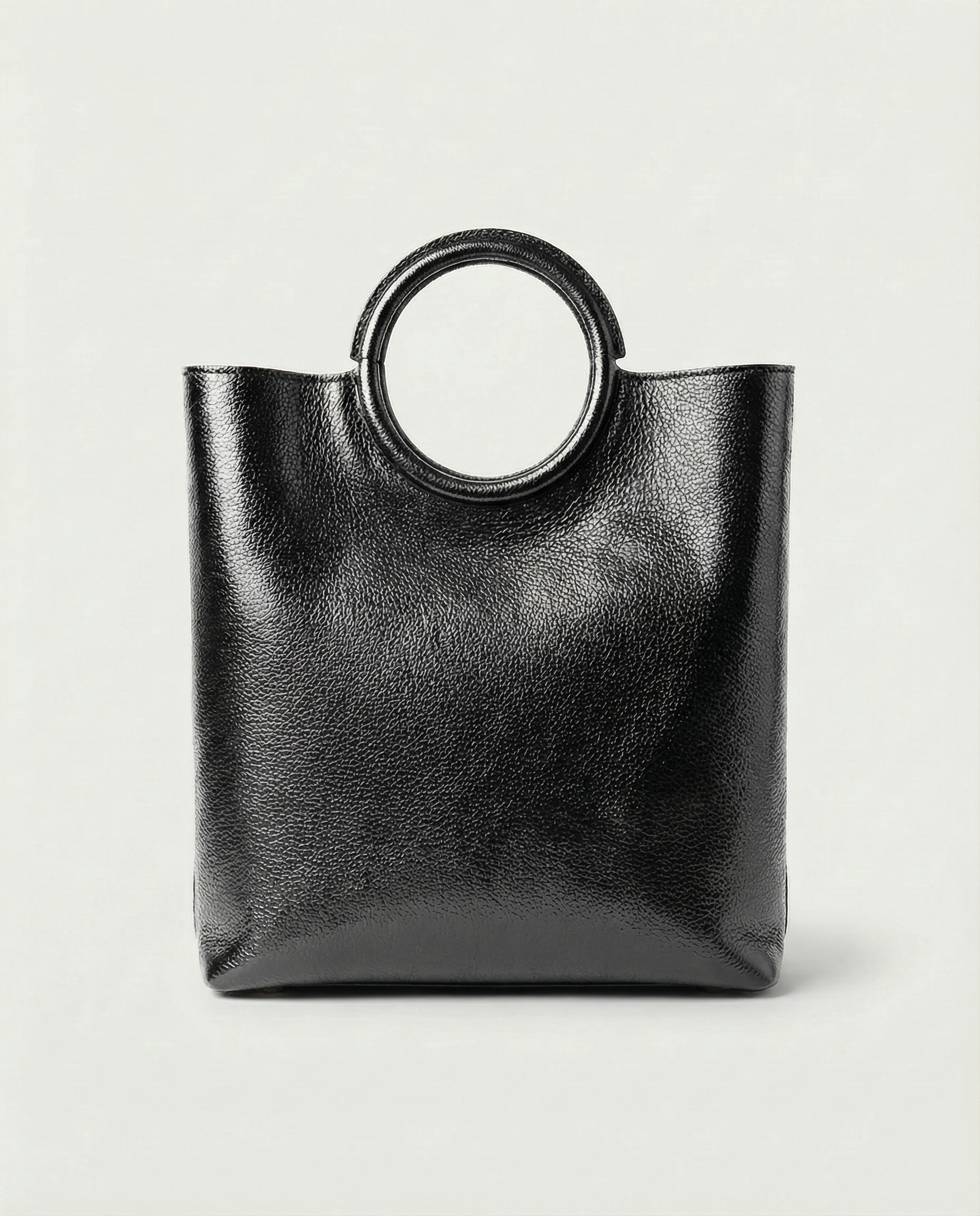 Metallic black leather ring bag with circular top handle and structured silhouette, sleek and modern design.