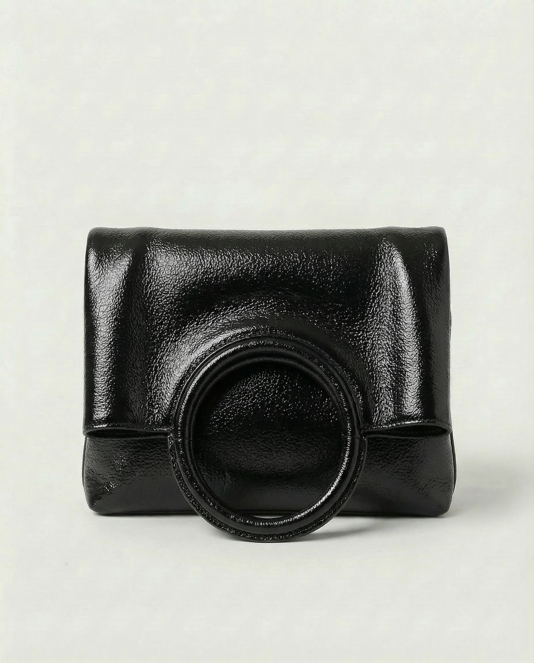 Metallic black leather ring bag with circular top handle and structured silhouette, sleek and modern design.
