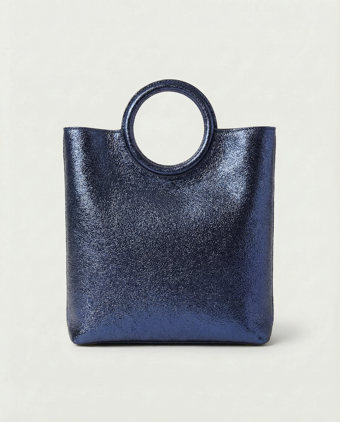 Metallic indigo leather ring bag with circular top handle and structured silhouette, sleek and modern design.