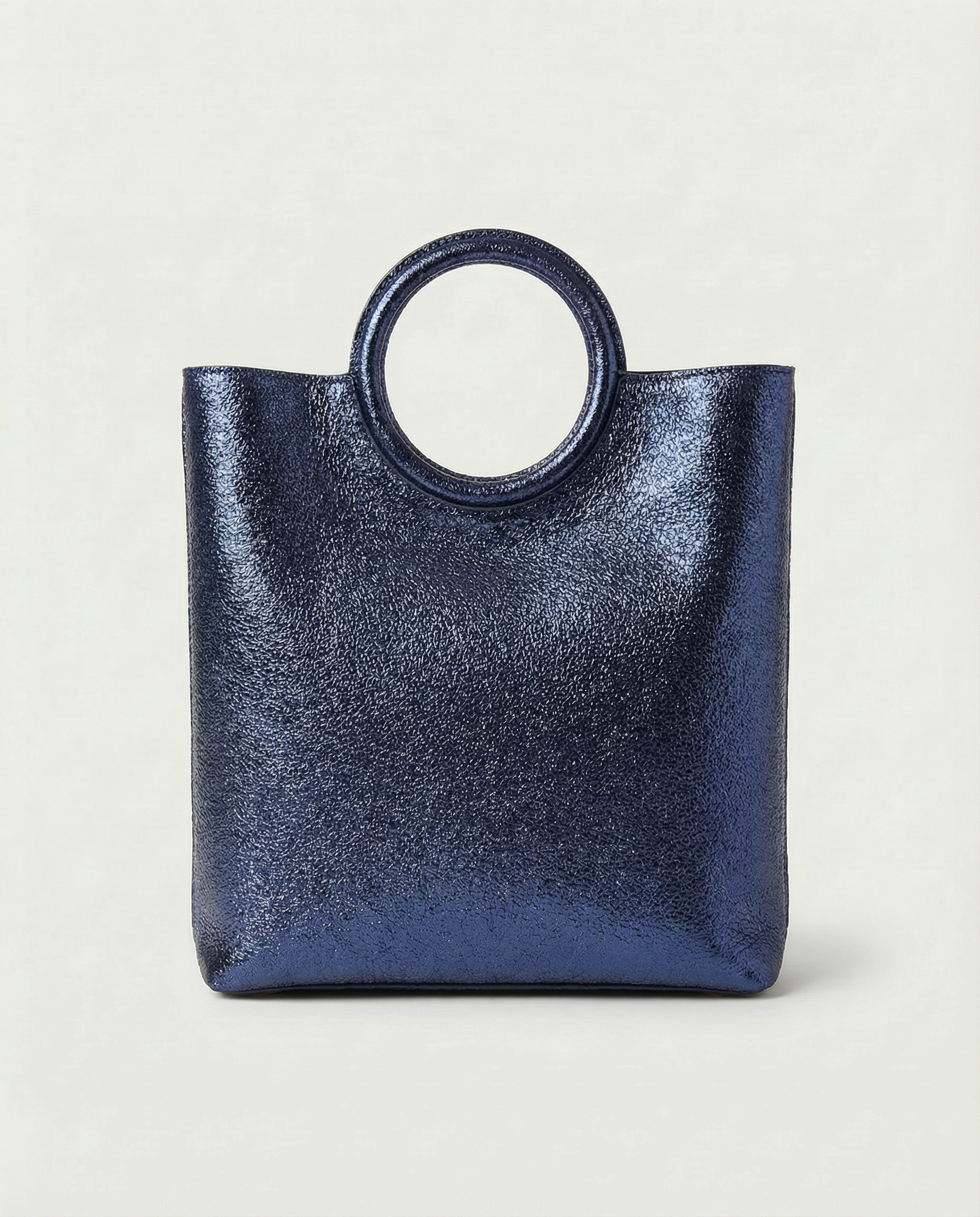 Metallic indigo leather ring bag with circular top handle and structured silhouette, sleek and modern design.