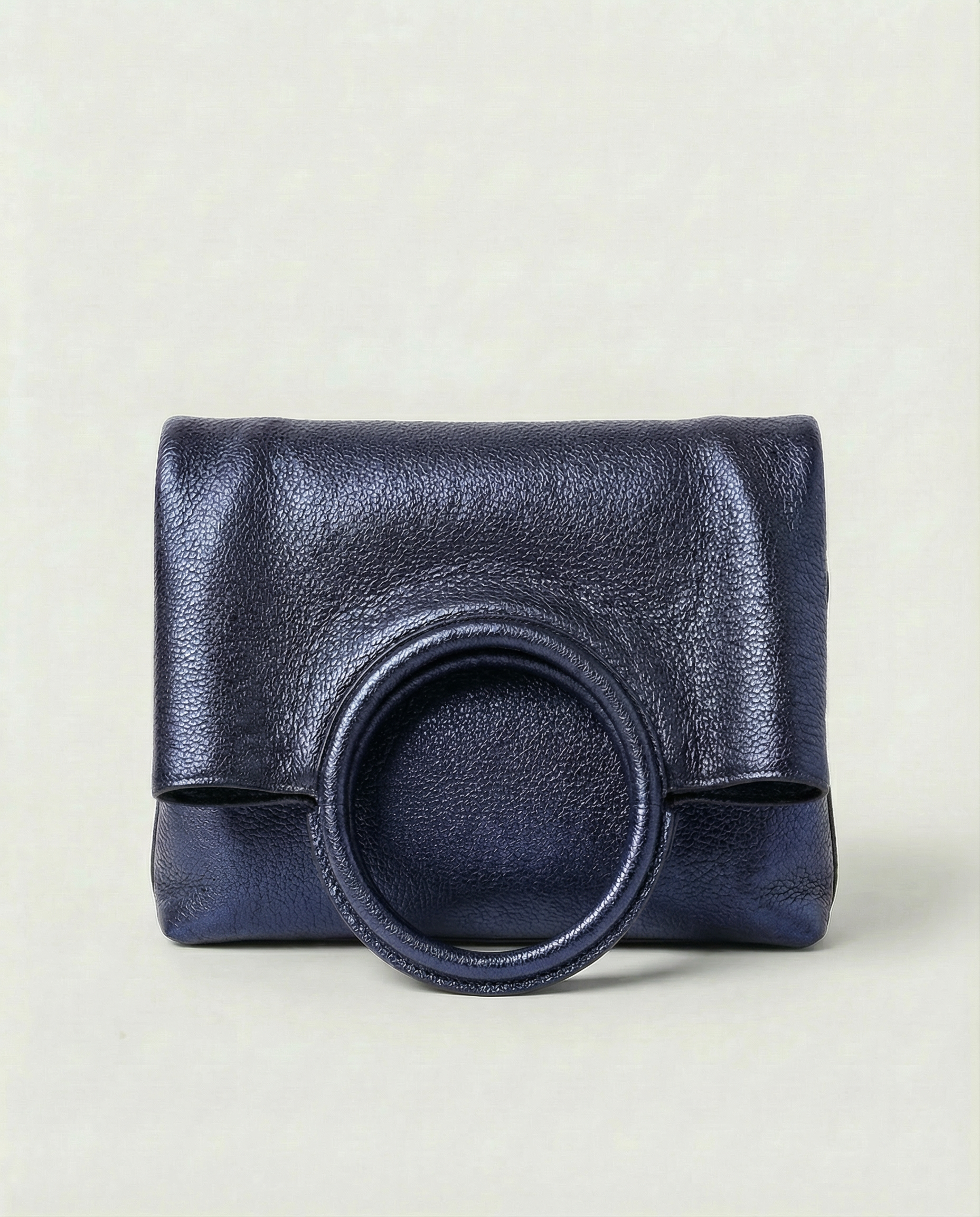 Metallic indigo leather ring bag with circular top handle and structured silhouette, sleek and modern design.