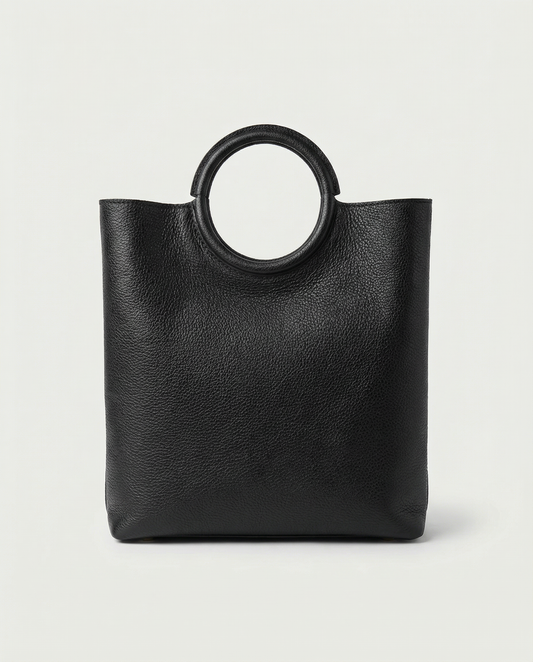 Ring Bag in pebble leather black with circular ring handle and structured silhouette.