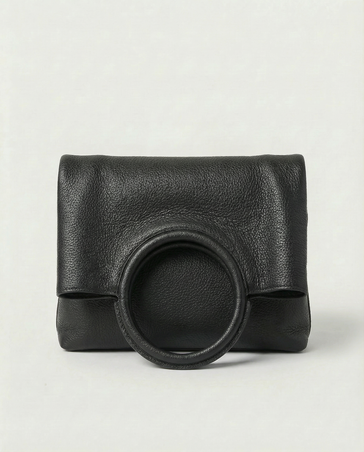 Ring Bag in pebble leather black with circular ring handle and structured silhouette.