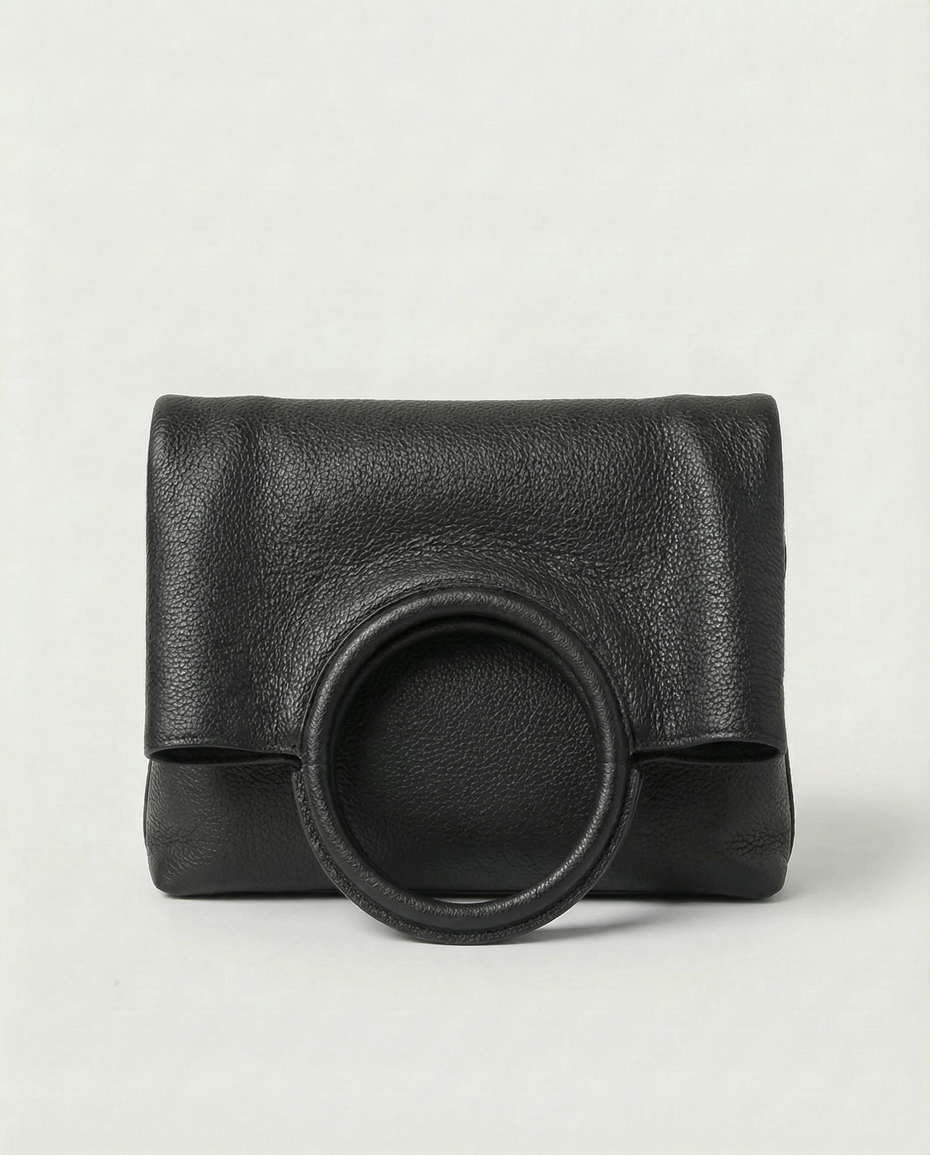 Ring Bag in pebble leather black with circular ring handle and structured silhouette.