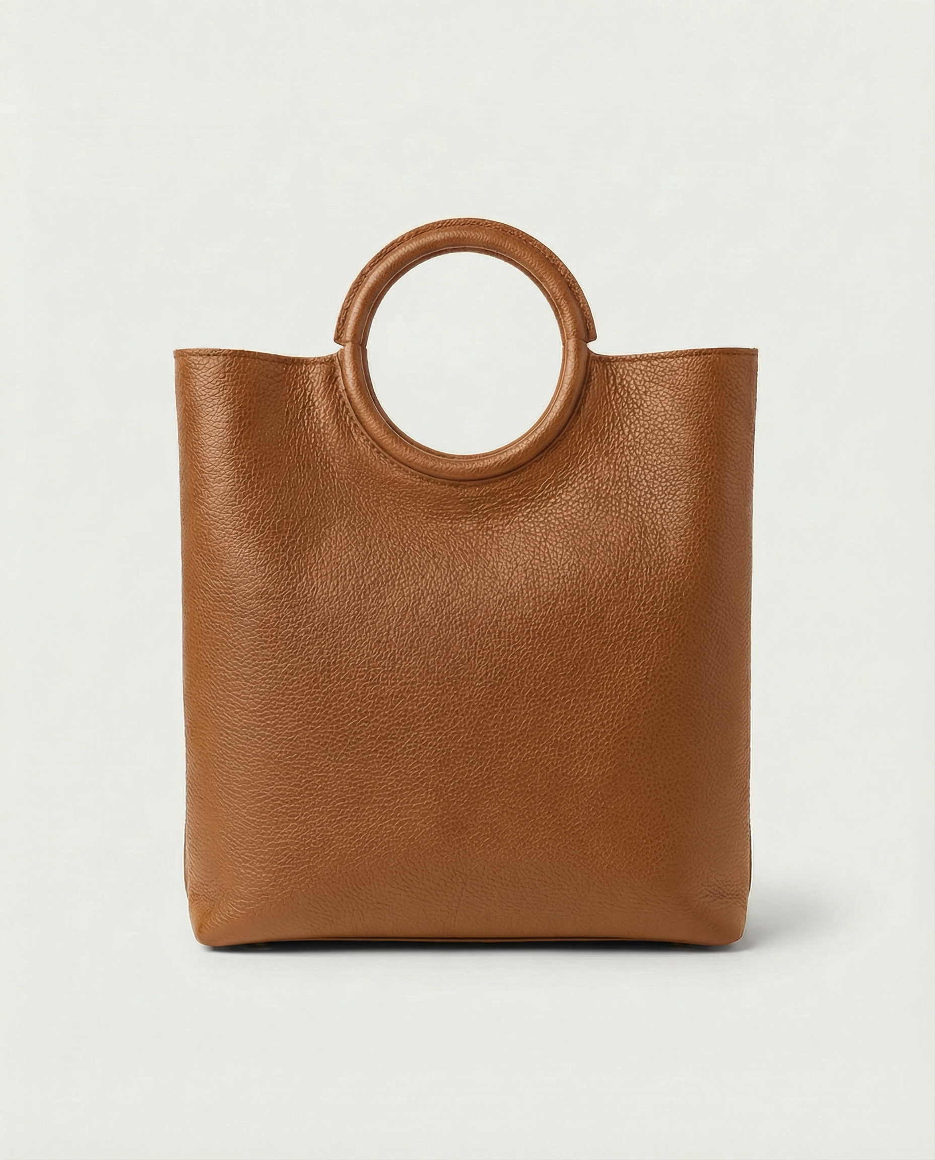 Ring Bag in pebble leather caramel with circular ring handle and structured silhouette.