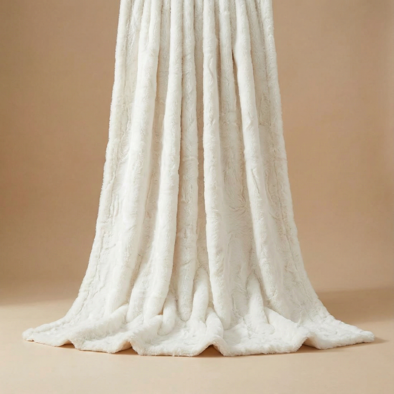 Ivory-colored faux rabbit throw blanket vertically draped, showcasing its ultra-soft texture and smooth, elegant folds against a warm neutral background.
