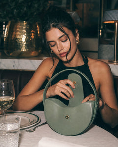 Woman carrying the Tourance Sorella circle bag in Verde Salvia, view 2